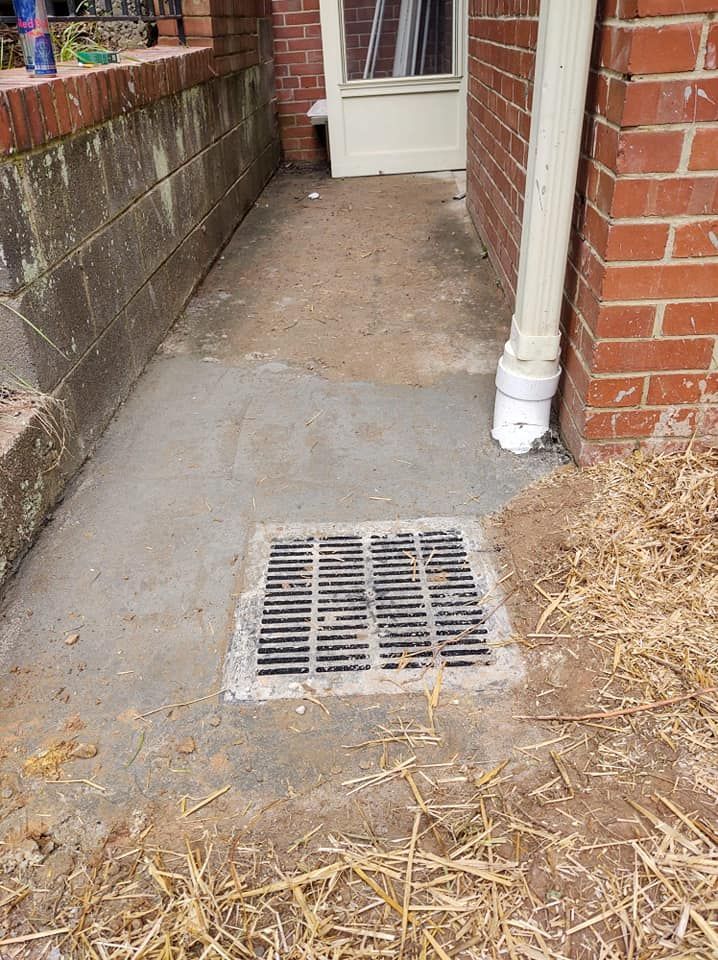 A drain on the side of a building next to a brick wall.