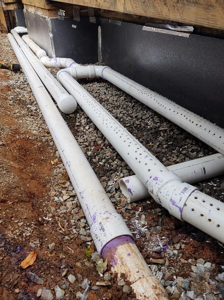 A bunch of white pipes are laying on the ground.