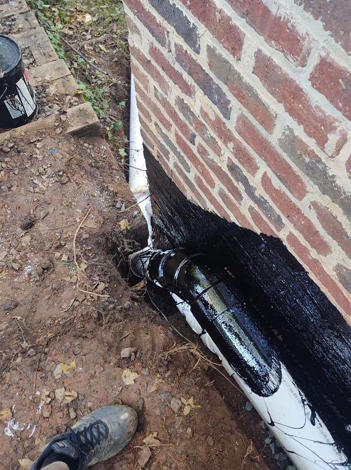 A person is painting a brick wall with a brush.