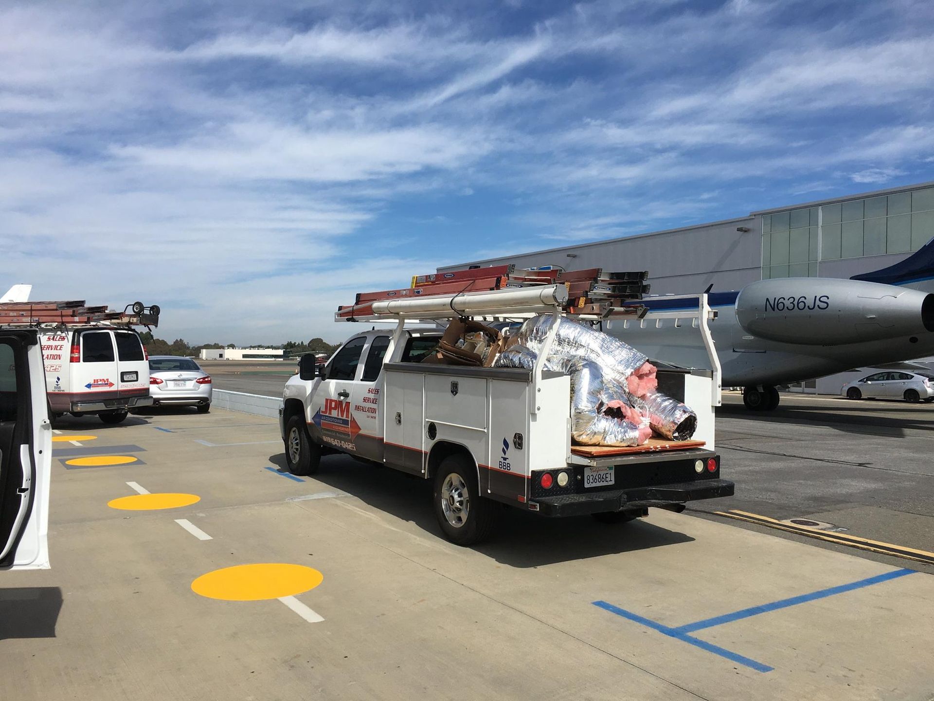 A white truck is parked on a runway next to a plane.