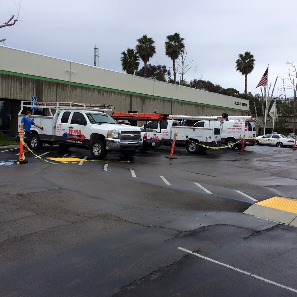 A row of utility trucks are parked in a parking lot