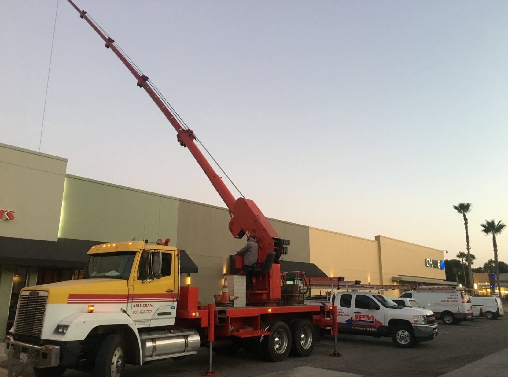 A crane truck is parked in front of a building
