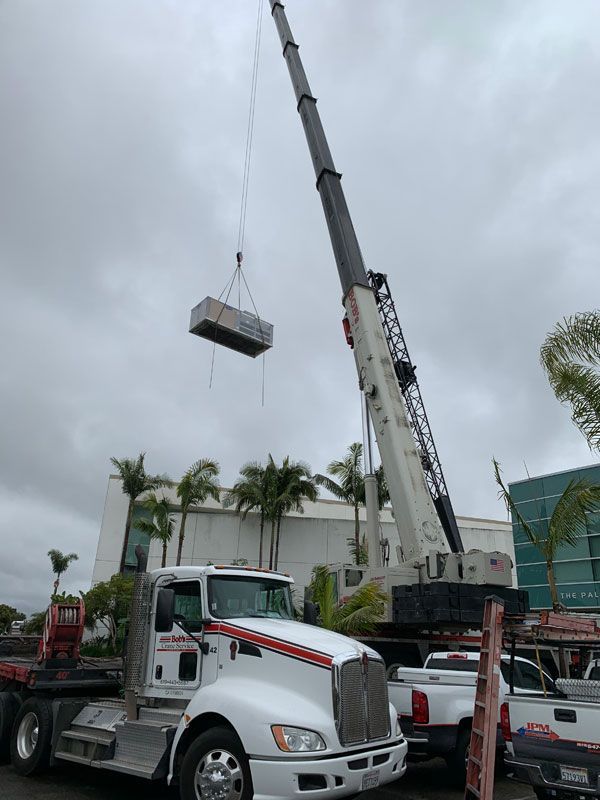 A truck with a crane attached to it is lifting a box.