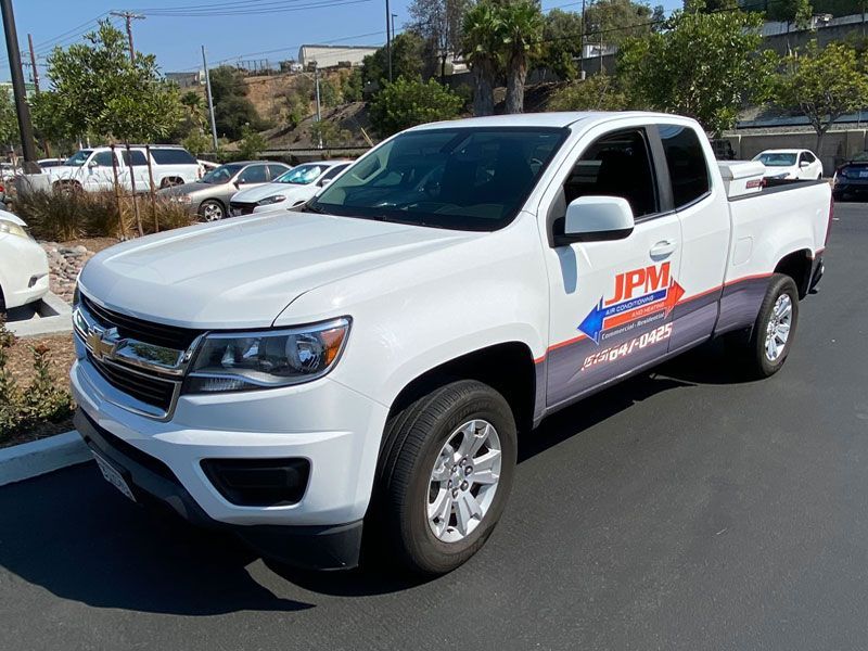 A white truck with jpm written on the side is parked in a parking lot.