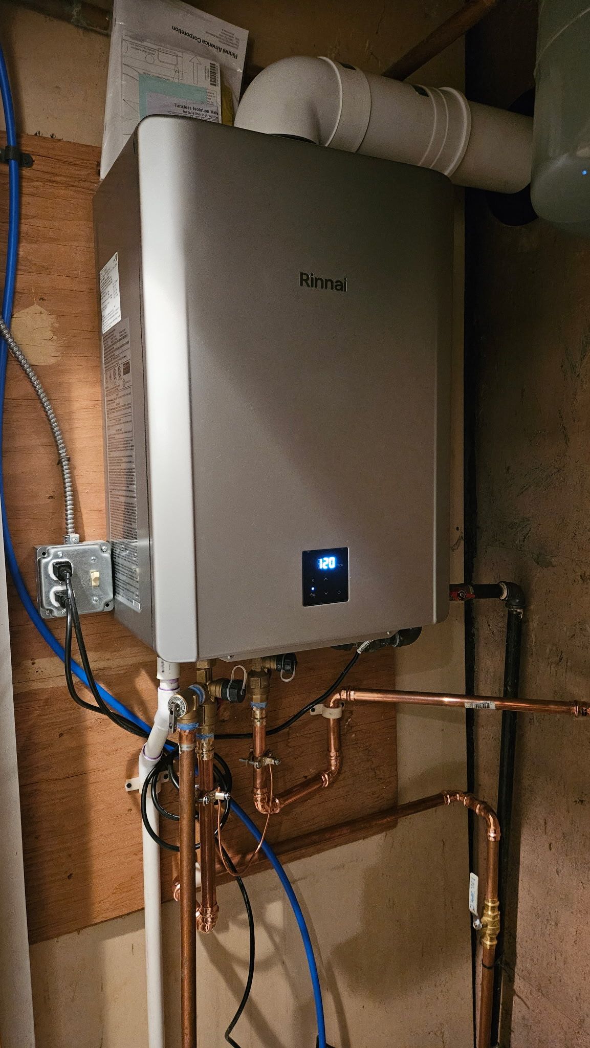 Wall-mounted utility box in a basement with exposed pipes and wiring.