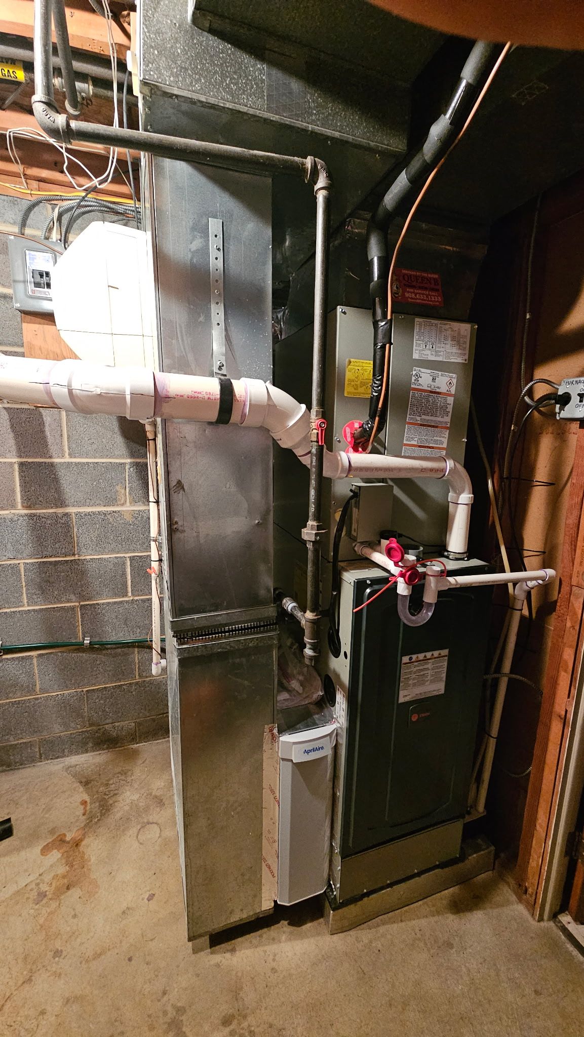 Basement HVAC furnace and ductwork beside utility pipes and insulation