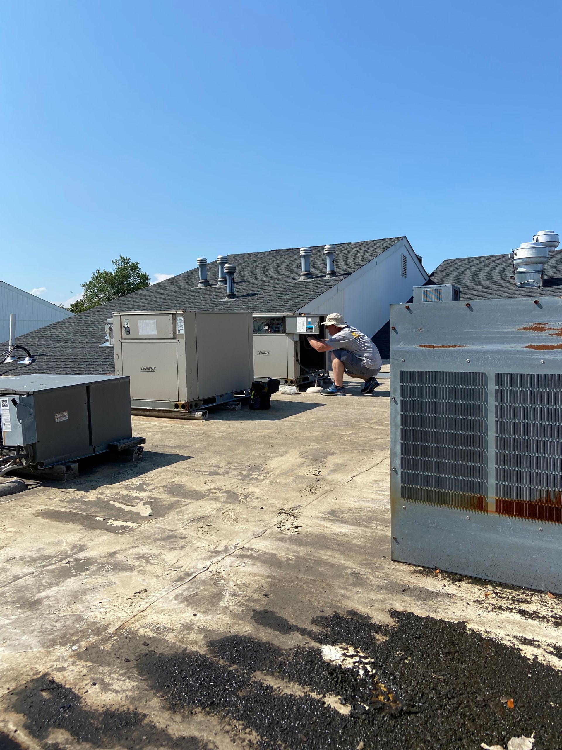 Outdoor industrial site with utility trailers and debris under a clear blue sky, damaged structures in background