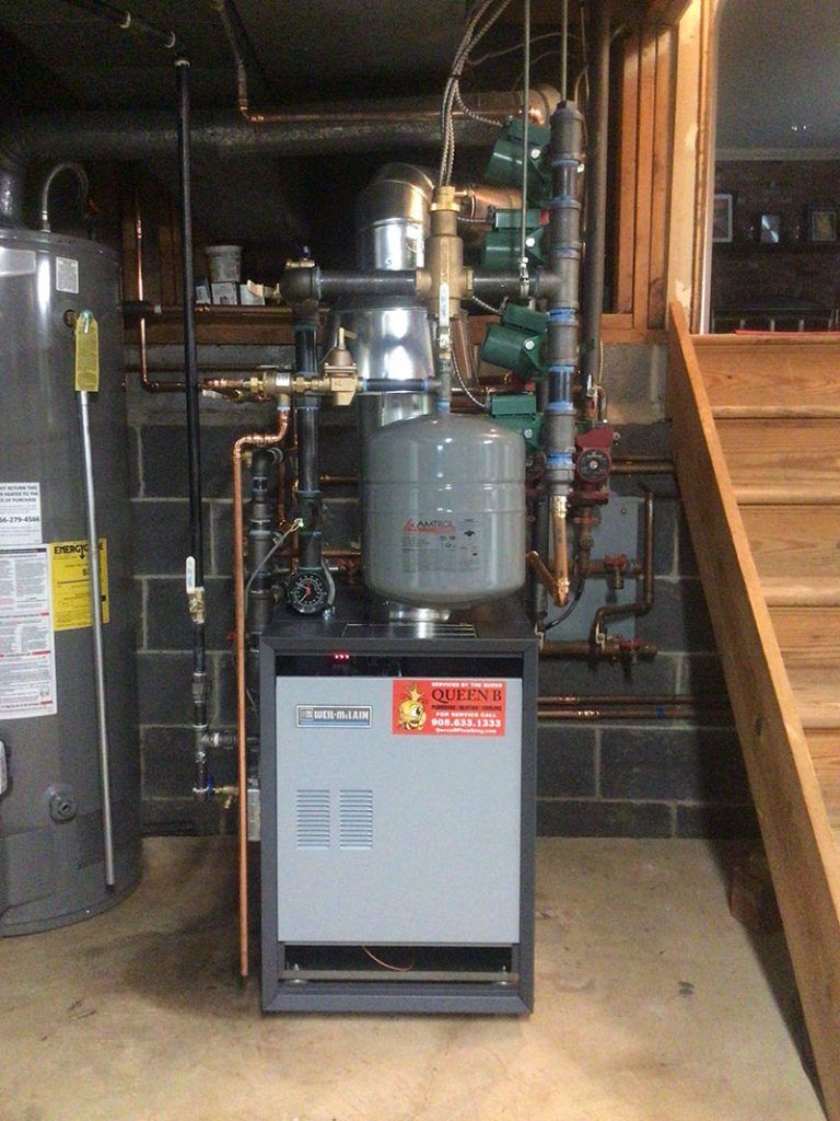 Basement utility room with boiler, water heater, pipes, and furnace beside stairs