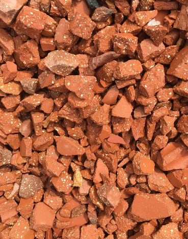 Red-brown crushed rock gravel, possibly brick or terracotta, with small white flecks.
