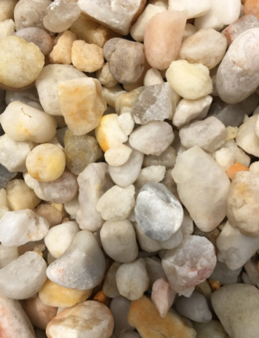 Close-up of a pile of rounded, mixed-color gravel, including white, tan, and peach stones.