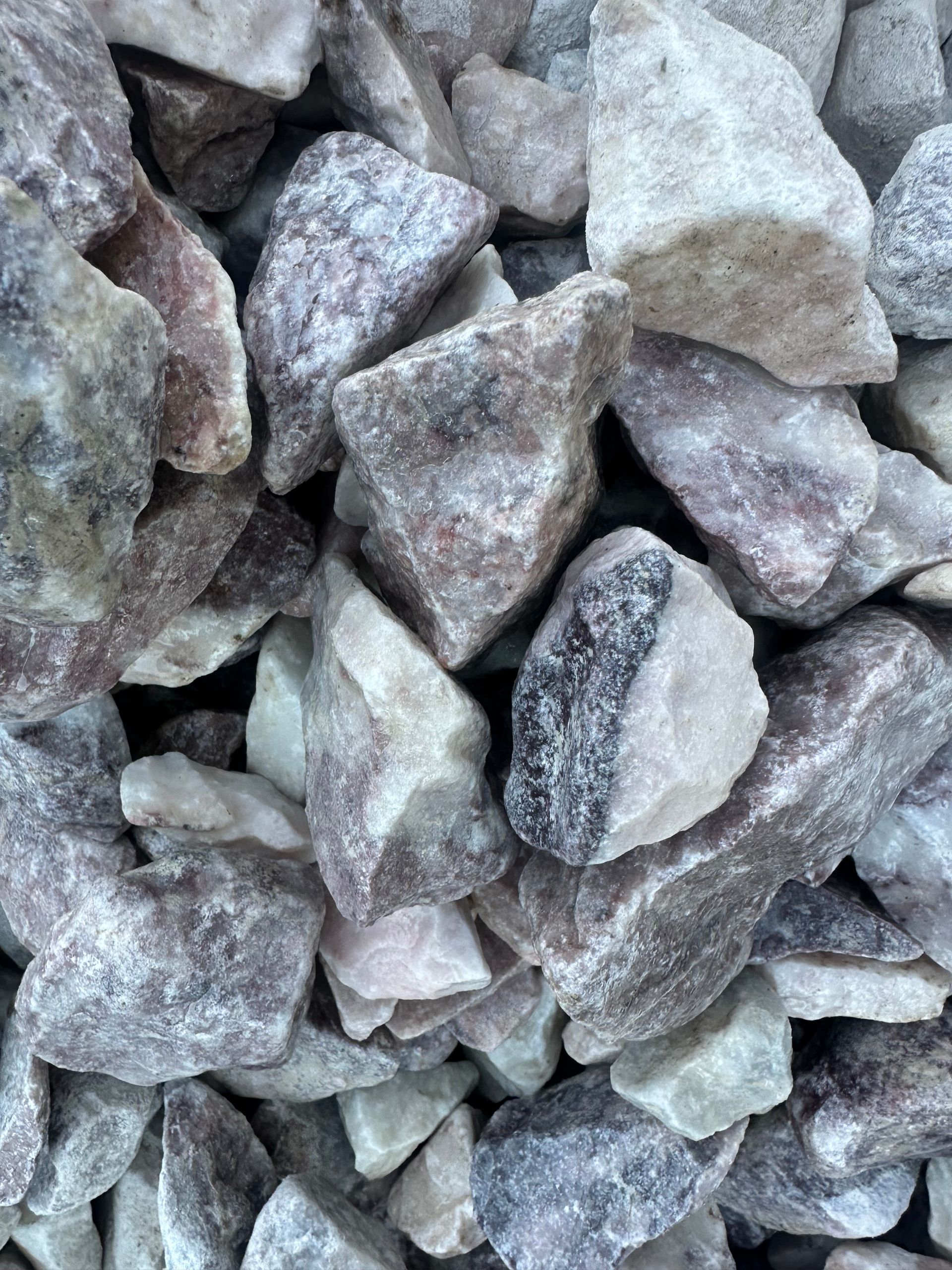 Pile of light gray and pinkish-brown crushed stone, various sizes and shapes.