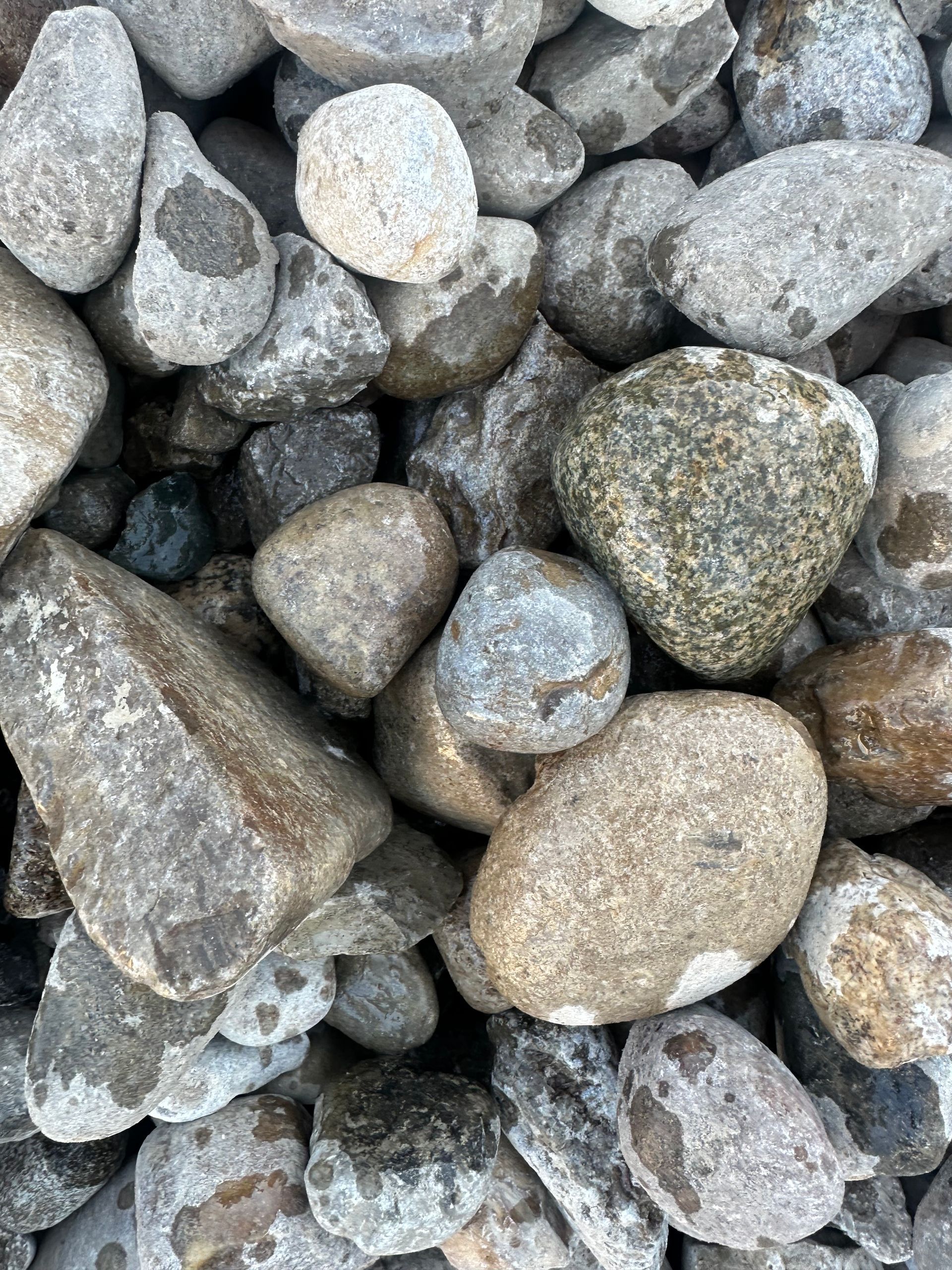 Pile of gray and tan river rocks, varying sizes and shapes.