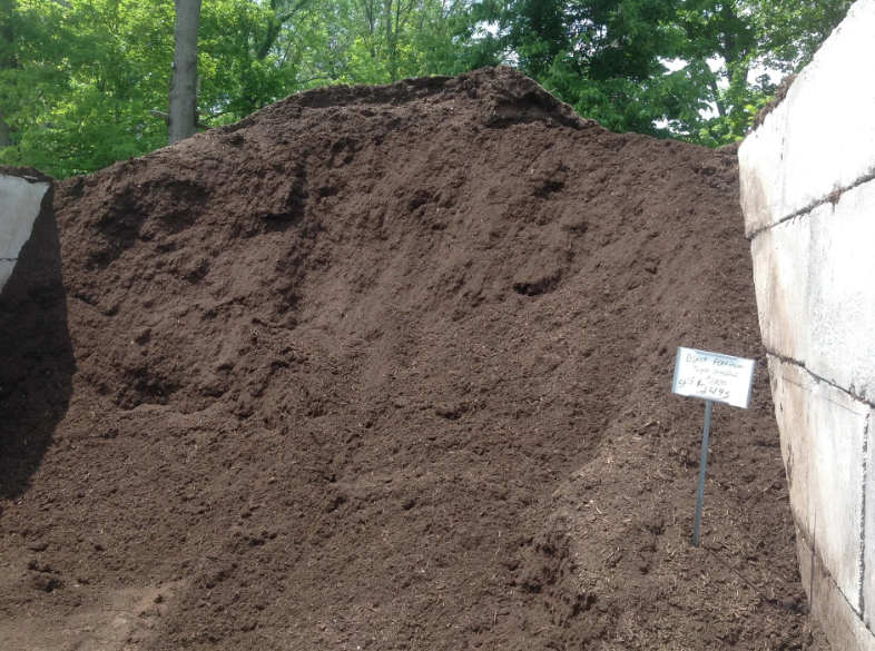 Pile of dark brown mulch with a sign.
