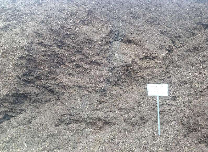 Pile of dark mulch with a small sign.
