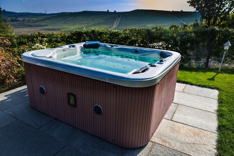 A large hot tub is sitting on a patio in a backyard.