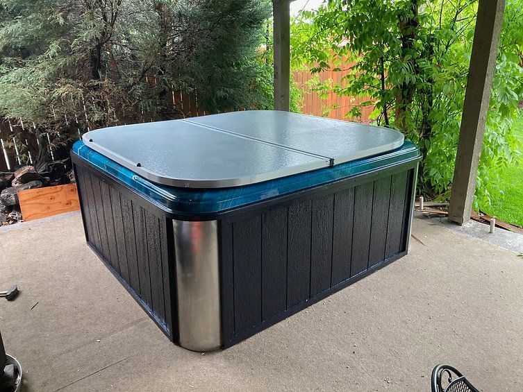 A hot tub is sitting on a patio under a canopy.
