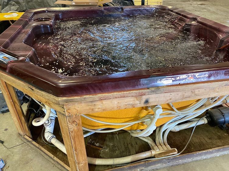 A hot tub is sitting in a wooden box filled with water.