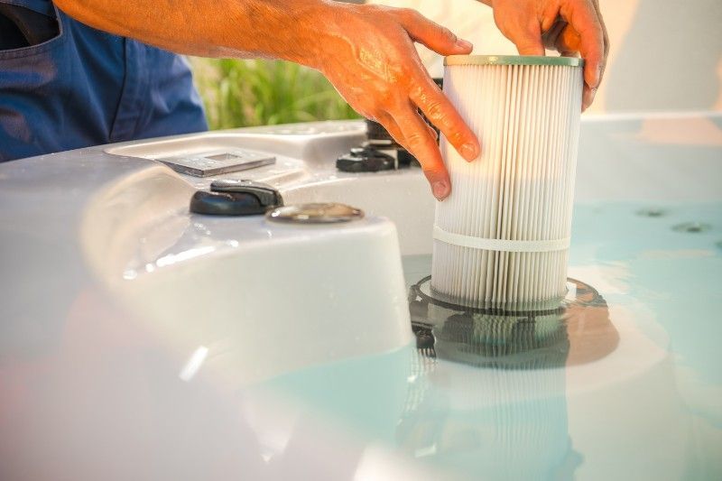A man is cleaning a hot tub filter in the water.