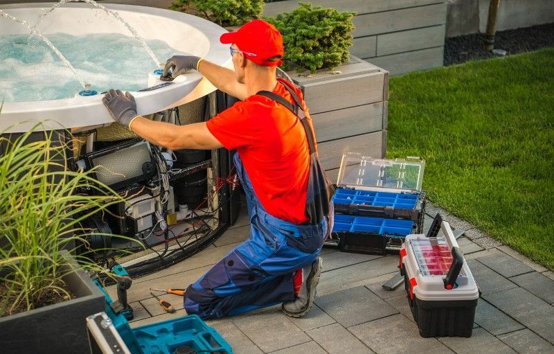 A man is working on a hot tub in a backyard.