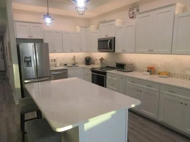 Bright white kitchen with stainless steel appliances and a large island counter