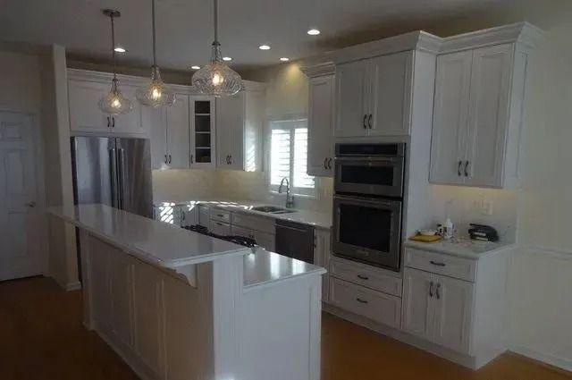 Modern kitchen with white cabinets, island, stainless steel appliances, and pendant lights