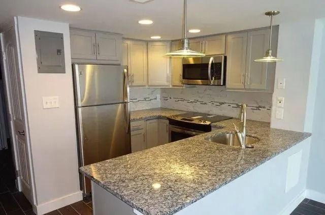 Modern kitchen with stainless steel appliances, granite island, and pendant lights