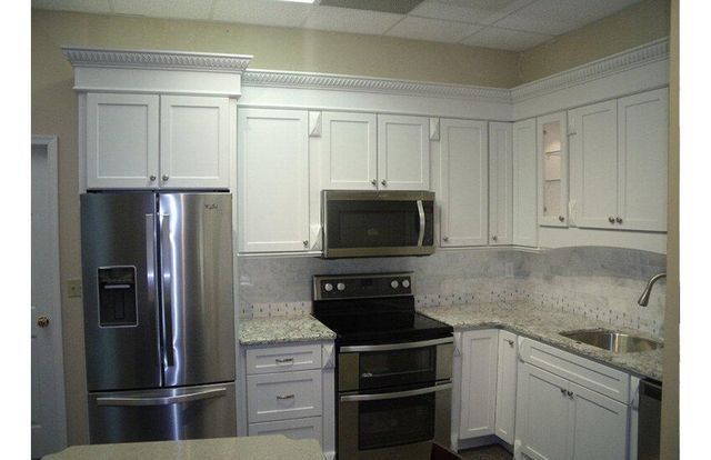 Modern kitchen with white cabinets, stainless steel appliances, and light tiled backsplash.