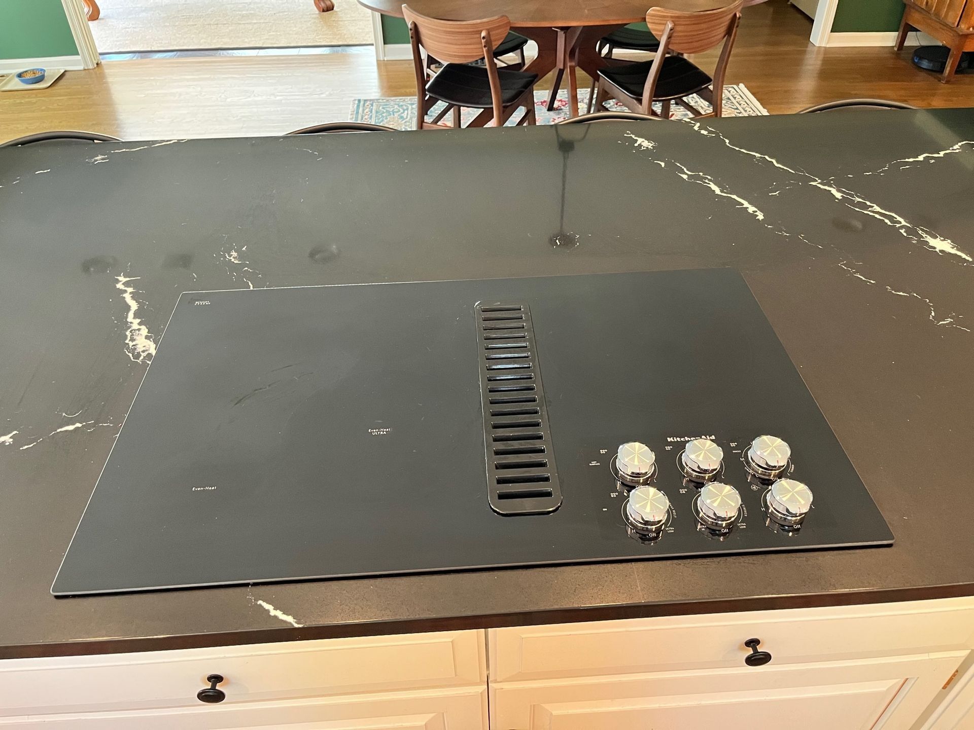 Black board game surface with a central track and clustered pieces on a kitchen island table