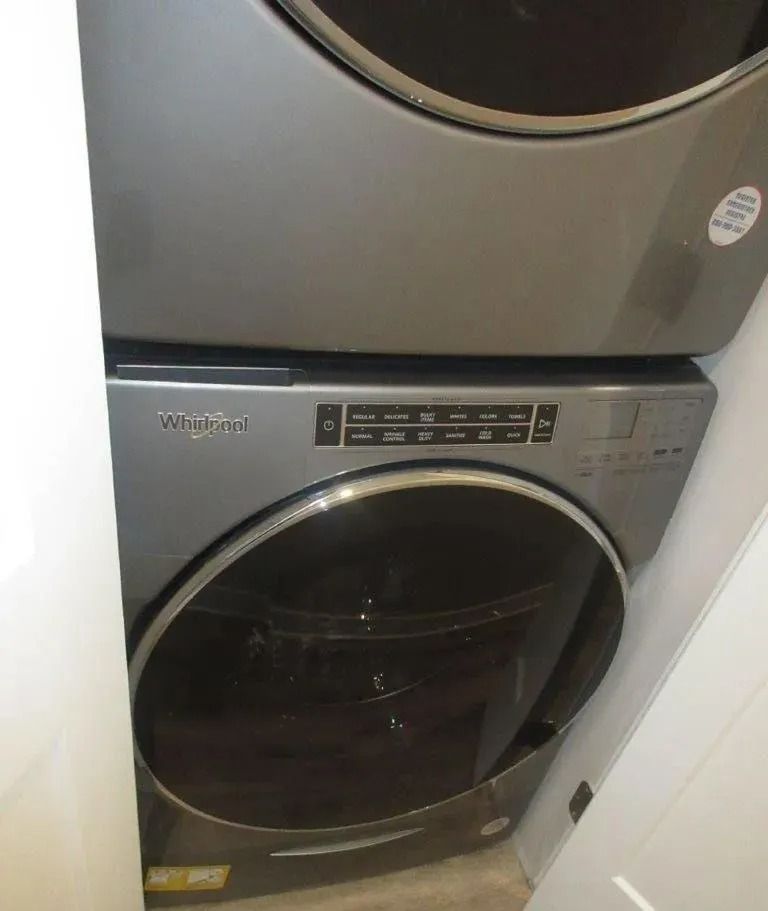 Gray front-loading washer and dryer stacked in a narrow laundry closet.