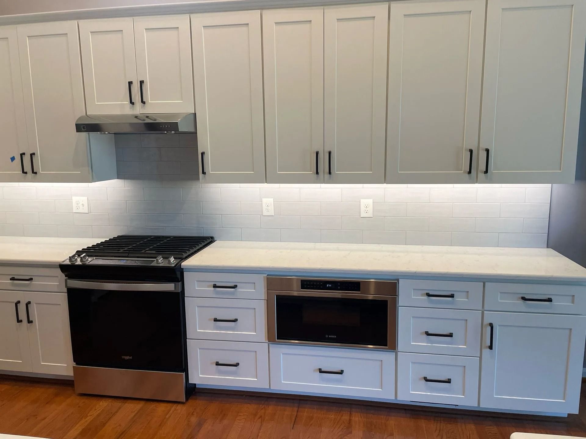 Modern kitchen with white cabinets, black stove, and light wood floor