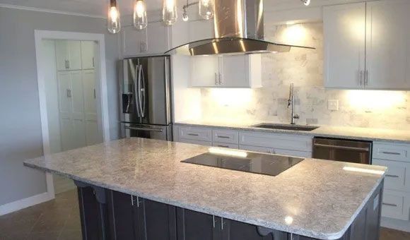 Modern kitchen with large island, marble countertops, stainless steel appliances, and pendant lights