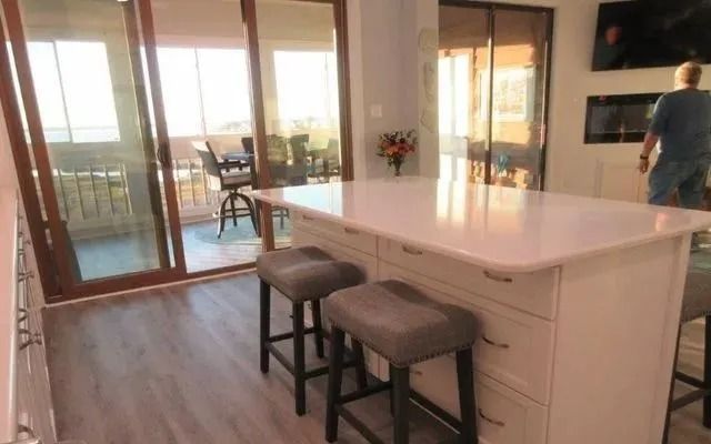 Modern kitchen with white island and two stools, sliding glass doors to a patio in the background