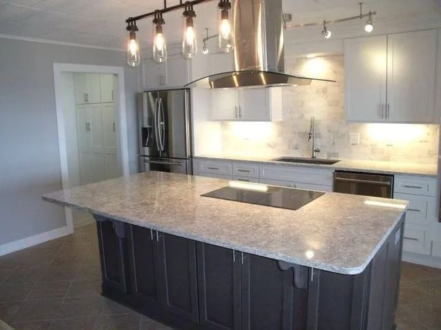 Modern kitchen with large island, stainless steel appliances, white cabinets, and pendant lighting