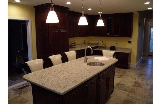 Modern kitchen with dark cabinets, stone island, pendant lights, and barstools