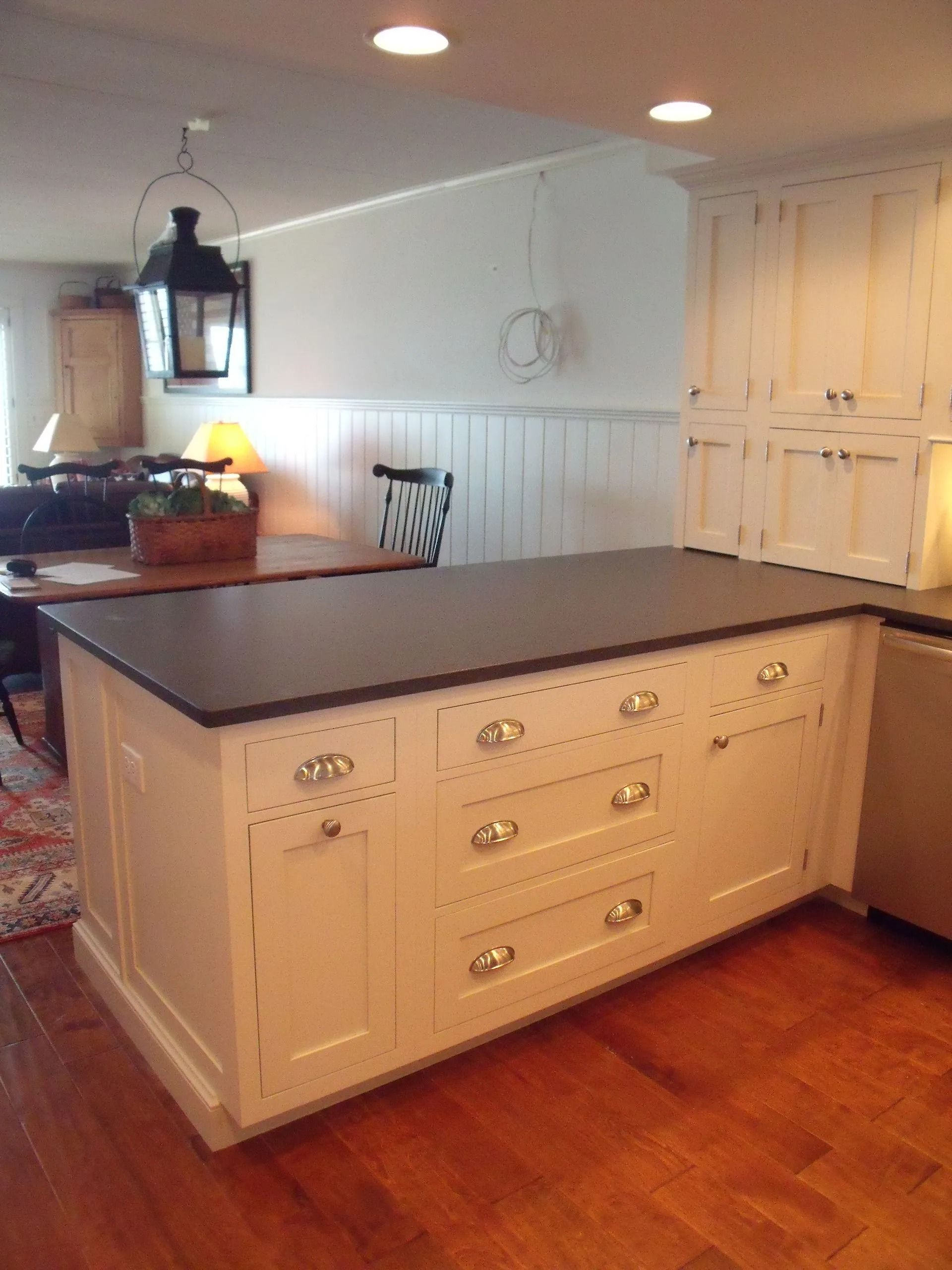Kitchen island with dark countertop and cream cabinets in a bright, hardwood-floored kitchen