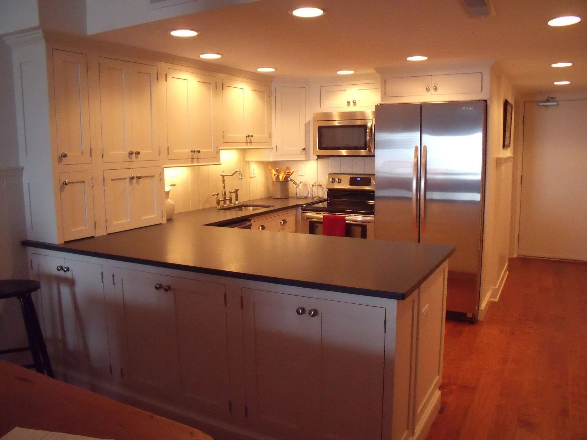 Bright modern kitchen with white cabinets, dark island countertop, and stainless steel appliances