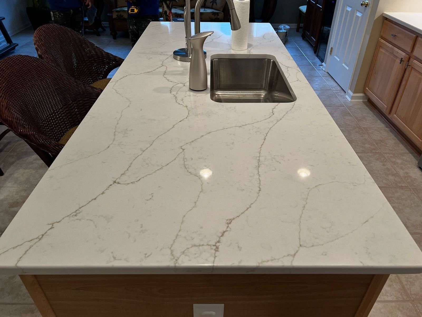 Kitchen island with white marble countertop and built-in sink under warm lights