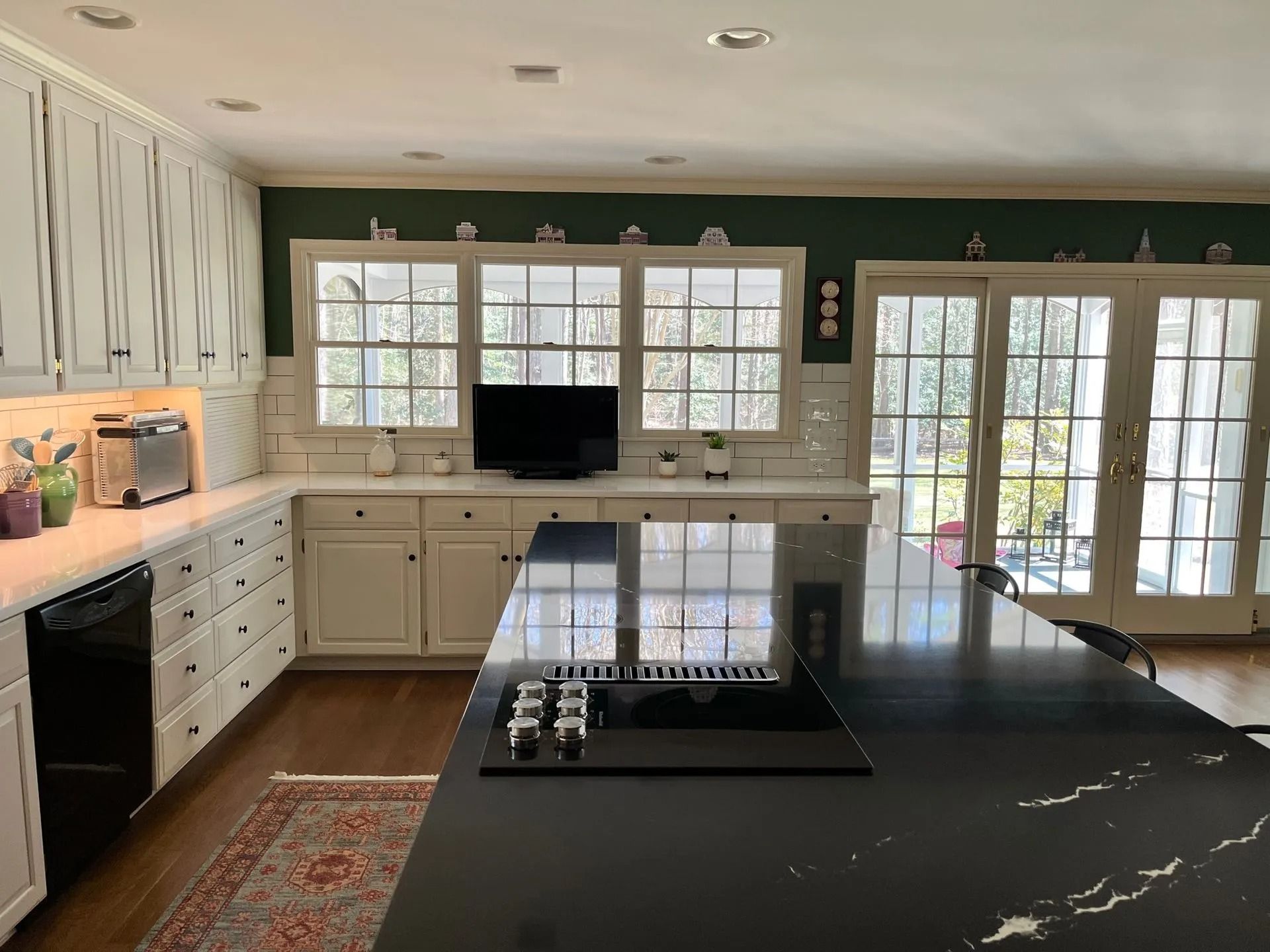 Modern kitchen with white cabinets, black island countertop, and glass doors opening to a patio