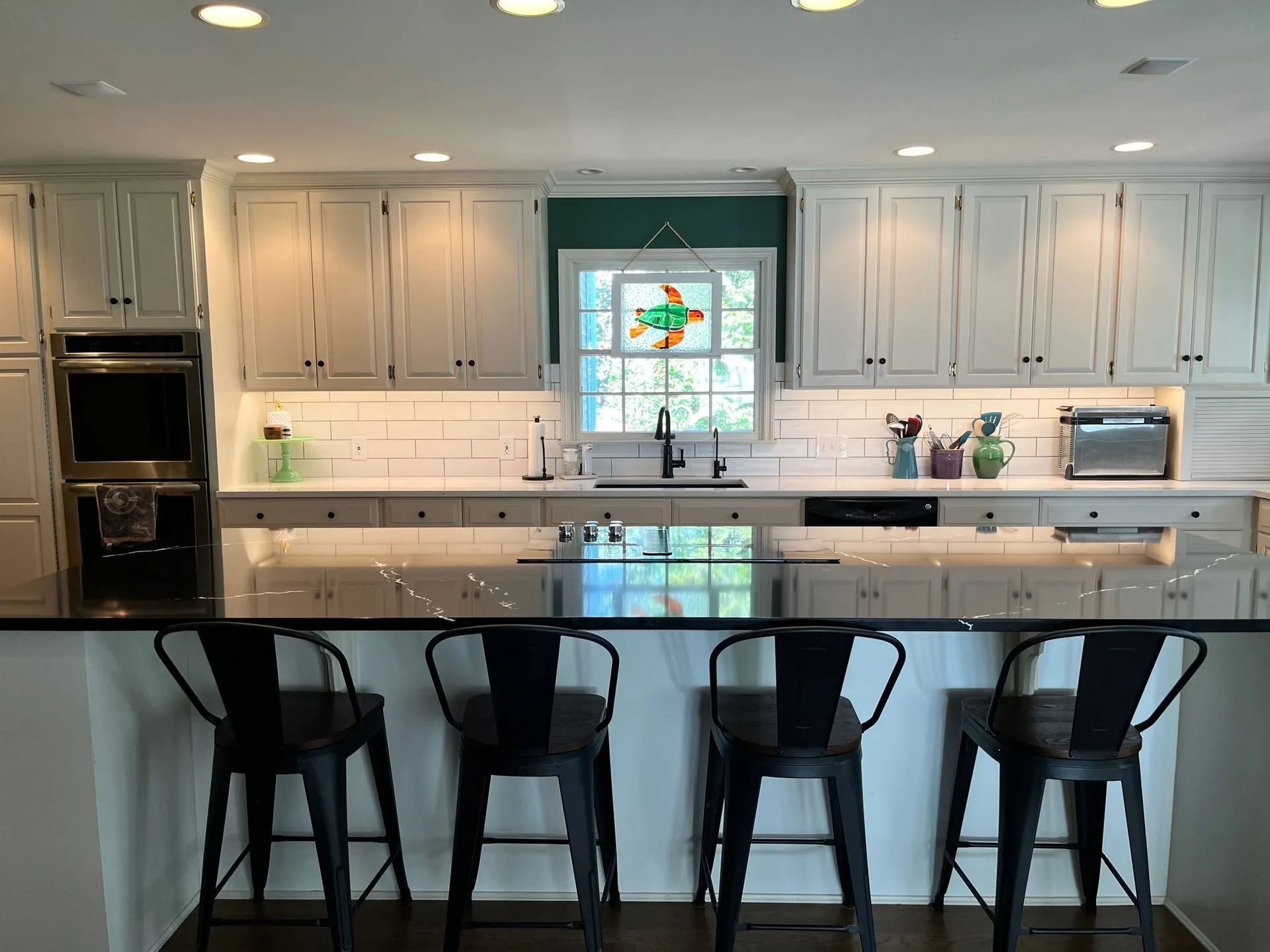 Modern white kitchen with island seating and large window over the sink