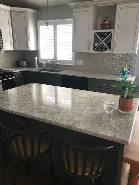 Modern kitchen with large island, granite countertops, white cabinets, and window over sink
