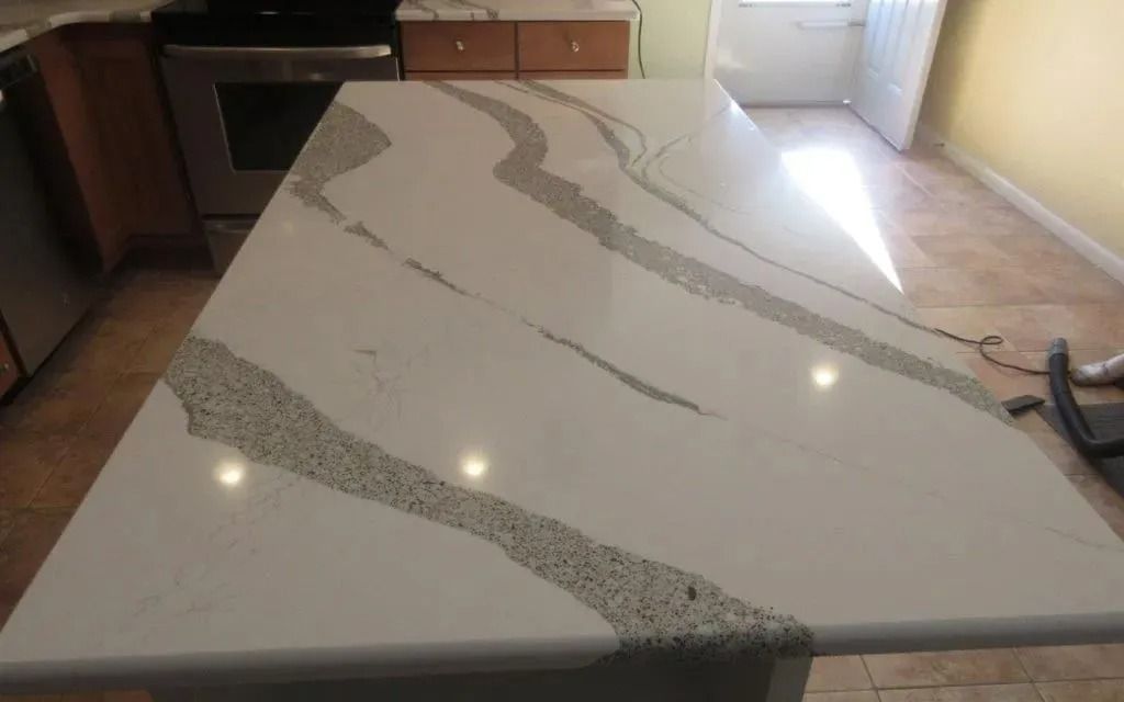 Kitchen countertop with white quartz and gray veining, installed and unfinished around the edges