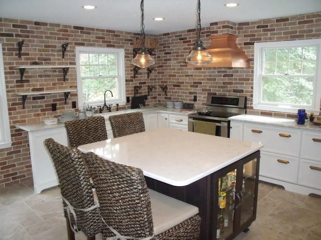 Modern kitchen with brick walls, white cabinets, island, and large windows