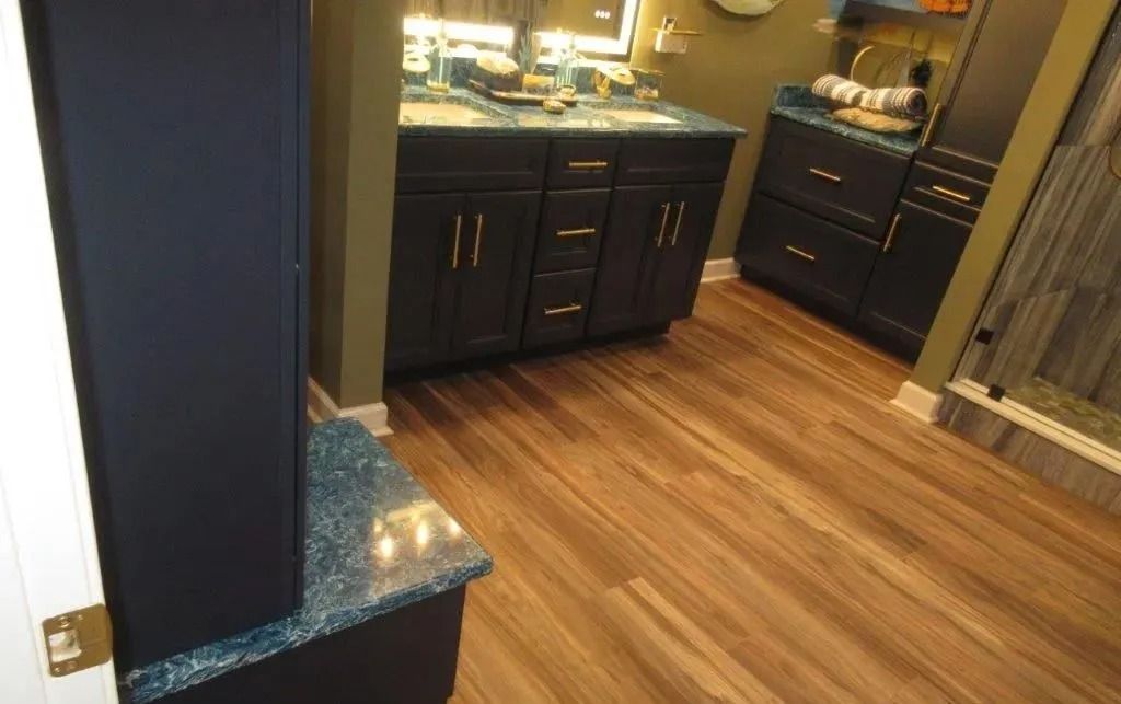 Empty kitchen area with dark cabinets, wood floor, and a granite countertop in the foreground