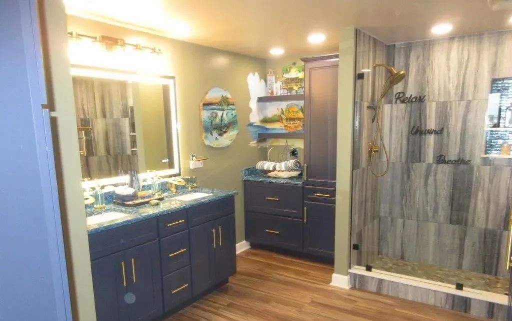 Blue bathroom vanity and shower with beige walls, lit mirror, and gray tiled shower curtain area
