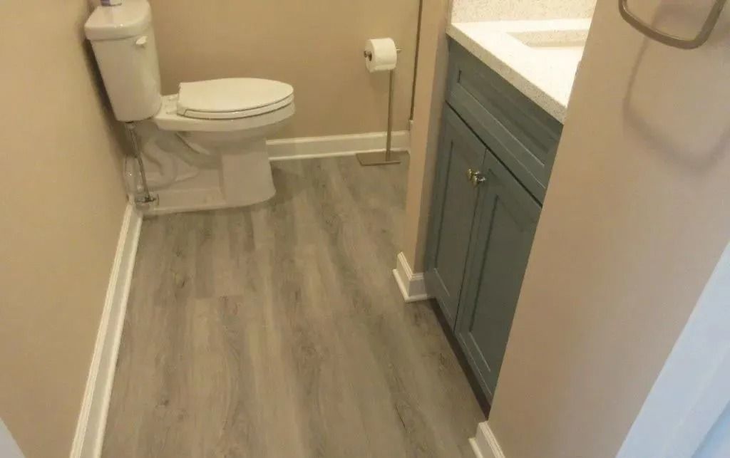 Small bathroom with toilet, vanity cabinet, and wood-look flooring.