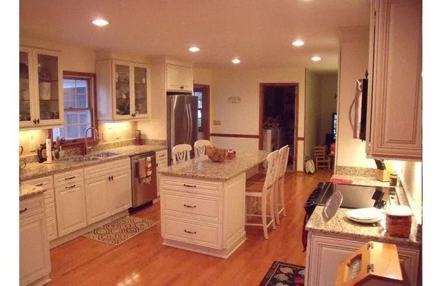 Bright kitchen with white cabinets, hardwood floors, central island, and stainless steel appliances