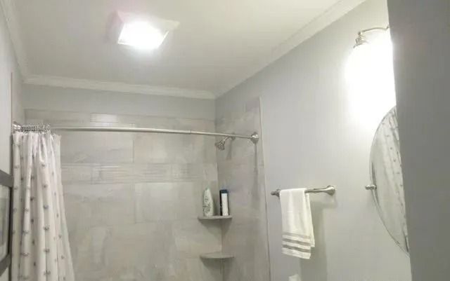 Small bathroom with a shower curtain, towel bar, wall shelf, and bright ceiling light