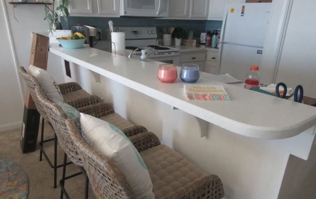 Kitchen with white island, patterned bar stools, and a refrigerator in the background