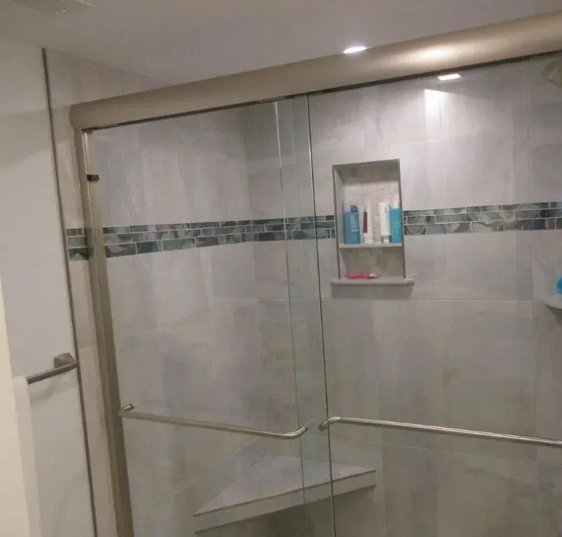 Glass shower enclosure with chrome handles and tiled bathroom walls
