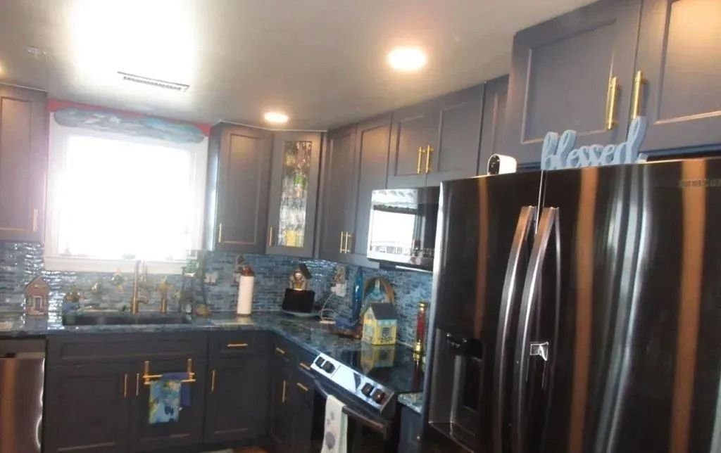 Modern kitchen with dark cabinets, stainless steel appliances, and blue tile backsplash